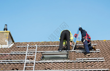 把太阳能电池板安装在屋顶上的工人高清图片
