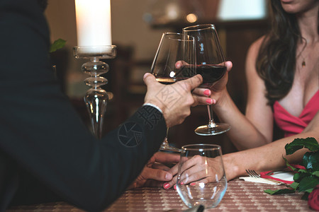 一对情侣握手喝着葡萄酒在一家餐馆的浪漫晚宴上降低音调红色的玫瑰奢华图片