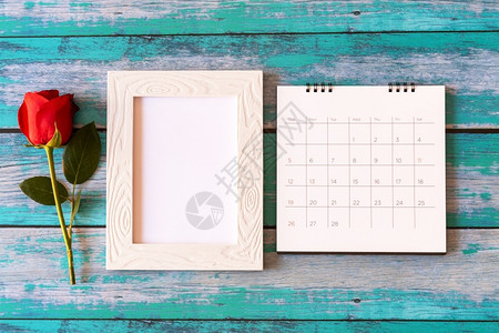 木制桌上的空白照片框日历和红玫瑰空的桌子美丽图片