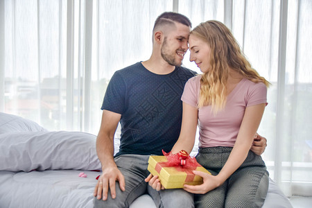 在情人节概念中爱情夫妇在卧室里赠送礼物盒的幸福气球浪漫展示图片