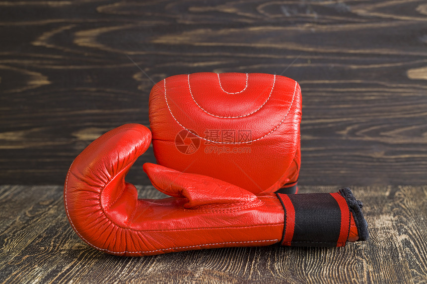 一对红色拳击手套躺在黑木板上涂有油漆的运动用品戴上一双红拳击手套竞争的绞刑运动员图片
