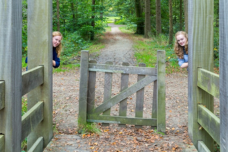 青年请享用俏皮两名天主教少女躲在徒步足迹的木脚入口处图片