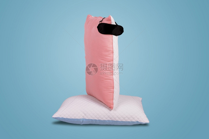 为了广告在蓝色背景的软坐垫上戴着睡蒙面罩的被切开枕头用于舒适睡眠和甜梦小憩图片