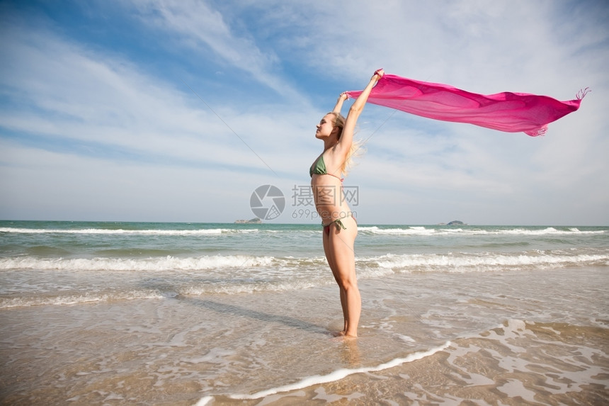 红色的游客海滩上有粉红色披肩的年轻美女丽图片