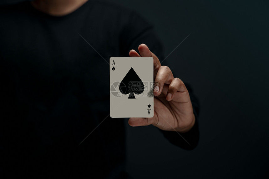 优胜者AceSpade持有扑克卡片前视图关闭和暗色调的人运气娱乐图片