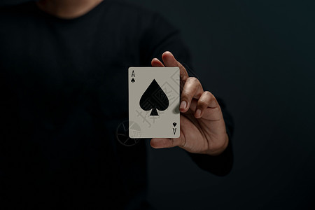 优胜者AceSpade持有扑克卡片前视图关闭和暗色调的人运气娱乐图片