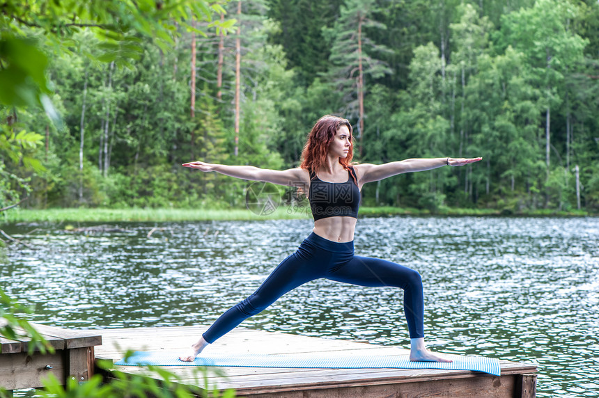 冥想娱乐年青的瑜伽女年站在武士2次练习中VirabhadrasanaII在健康生活和自然平衡概念湖面上出现户外图片
