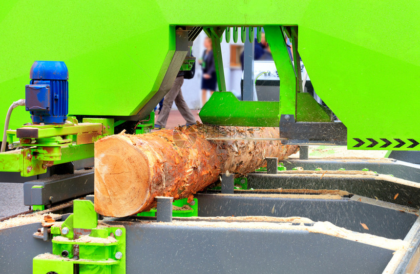 在现代锯木机上自动快速准确地切开大型松木日志并迅速和准确地在现代锯木机中自动快速和精确地剪切一个大松木日志磨材料图片
