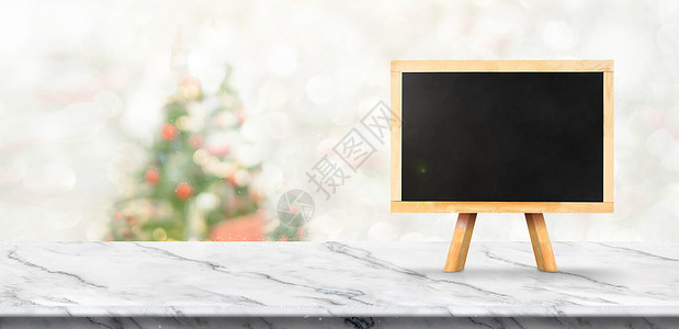 台面假期圣诞节横幅将黑板挂在白色大理石桌上圣诞树模糊雪落底用bokoh光条标语显示产品复制背景图片