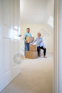 新的平坦老年夫妇在搬家日退休时递进新家的箱中降级人们背景图片