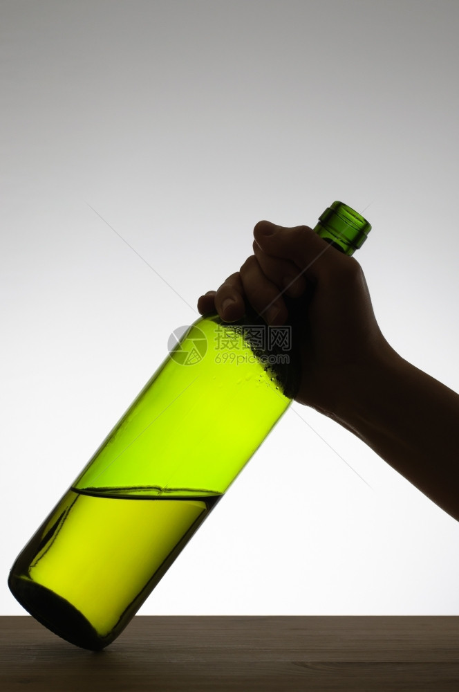 白色的黑暗握着一个绿色酒瓶的手摇轮子图片