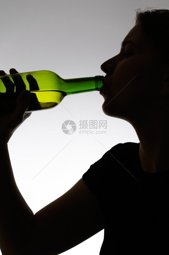 瘾挫折一个女人用瓶子喝葡萄酒的休眠精图片