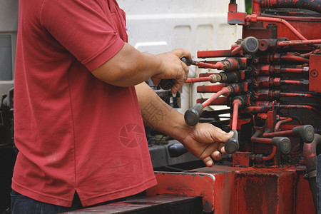 男人运输处理技术员手握控制着红色起重车的液压杠杆操作图片