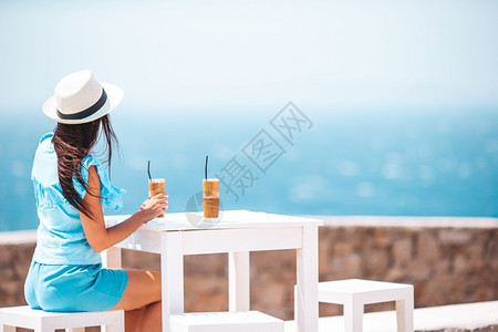 寒冷的在外咖啡厅喝冷享受海景的年轻女子喝冷咖啡享受海景的年轻女子士图片