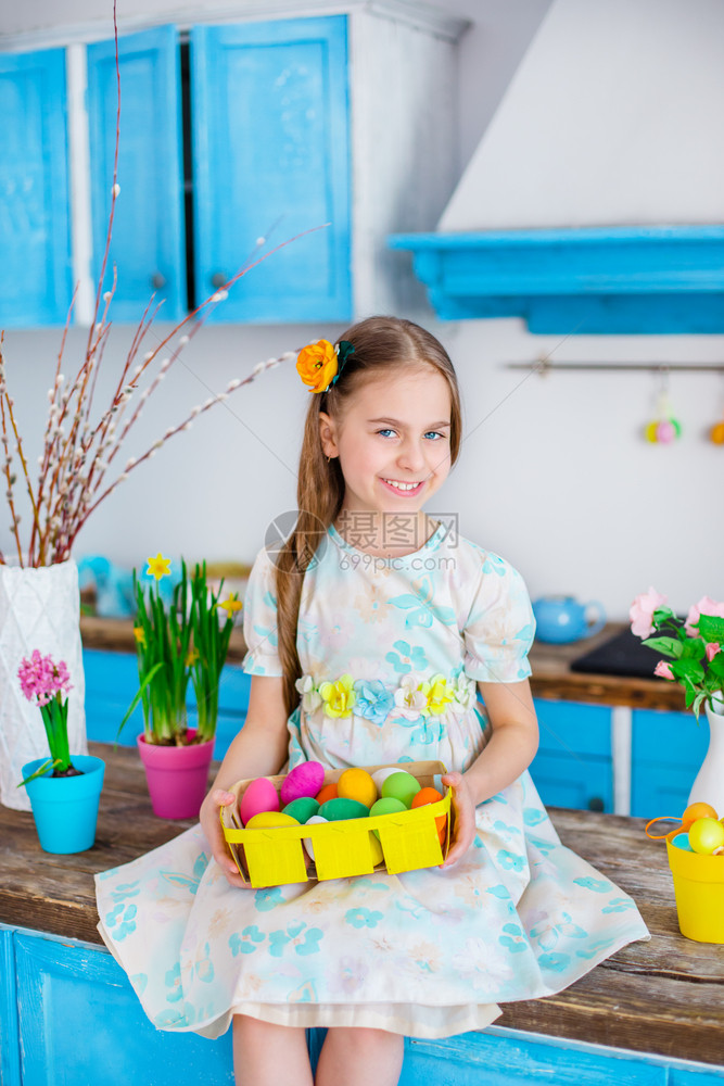 可爱的女孩拿着篮子和彩蛋在厨房煮饭为假日复活节可爱女孩做饭带彩蛋的篮子蓝色打猎家庭图片