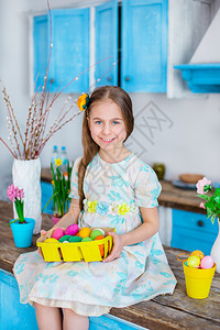 快乐的装饰可爱女孩拿着篮子和彩蛋在厨房煮饭为假日复活节可爱女孩做饭带彩蛋的篮子象征背景图片