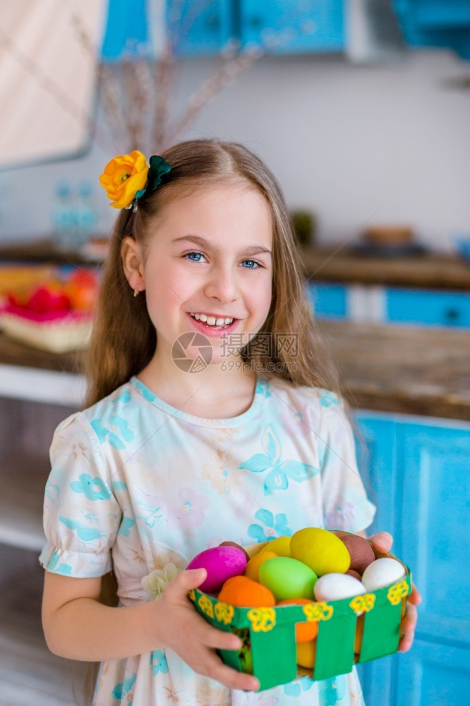 可爱的女孩拿着篮子和彩蛋在厨房煮饭为假日复活节可爱女孩做饭带彩蛋的篮子打猎季节传统图片