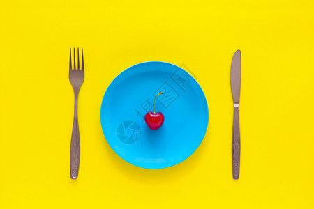 明亮的蓝盘刀叉黄底顶视平地夏天和饮食体重减肥的单一成熟樱桃盘子饥饿图片