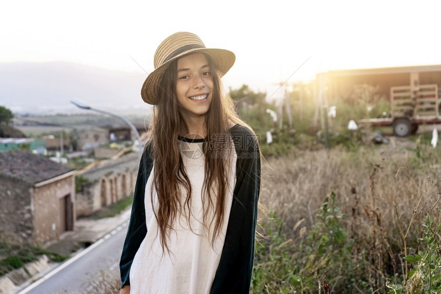 年轻快乐的青少旅行女孩穿着暑期服装和帽子站在户外看摄影机时着镜头可爱的夏天微笑图片
