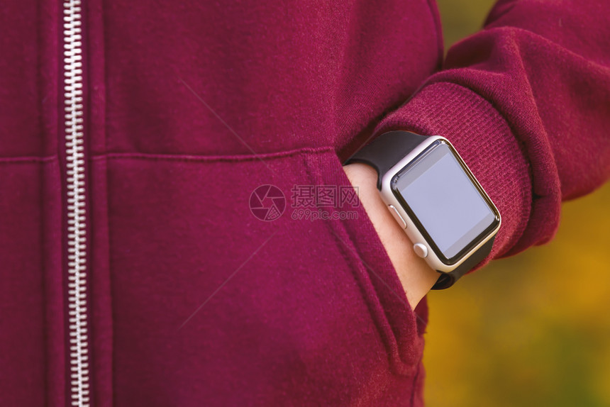白色的黄年轻女孩穿着聪明的手表握在口袋里关注智慧的手表指图片