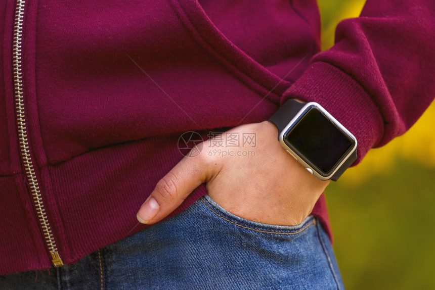 人们年轻女孩穿着聪明的手表握在口袋里关注智慧的手表腕女图片