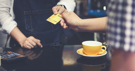 快乐的职业在咖啡店用信卡付咖啡费的是酒吧服务顾客和女招待读者图片