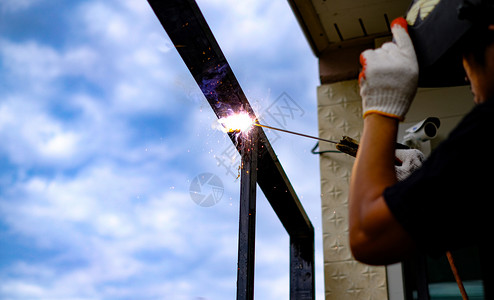 保护焊接技术员正在用燃烧的火花焊接钢铁使固定氩气图片
