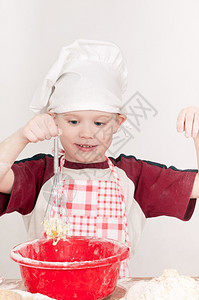 筛乐趣男孩在大厨帽子上打着面团桌图片