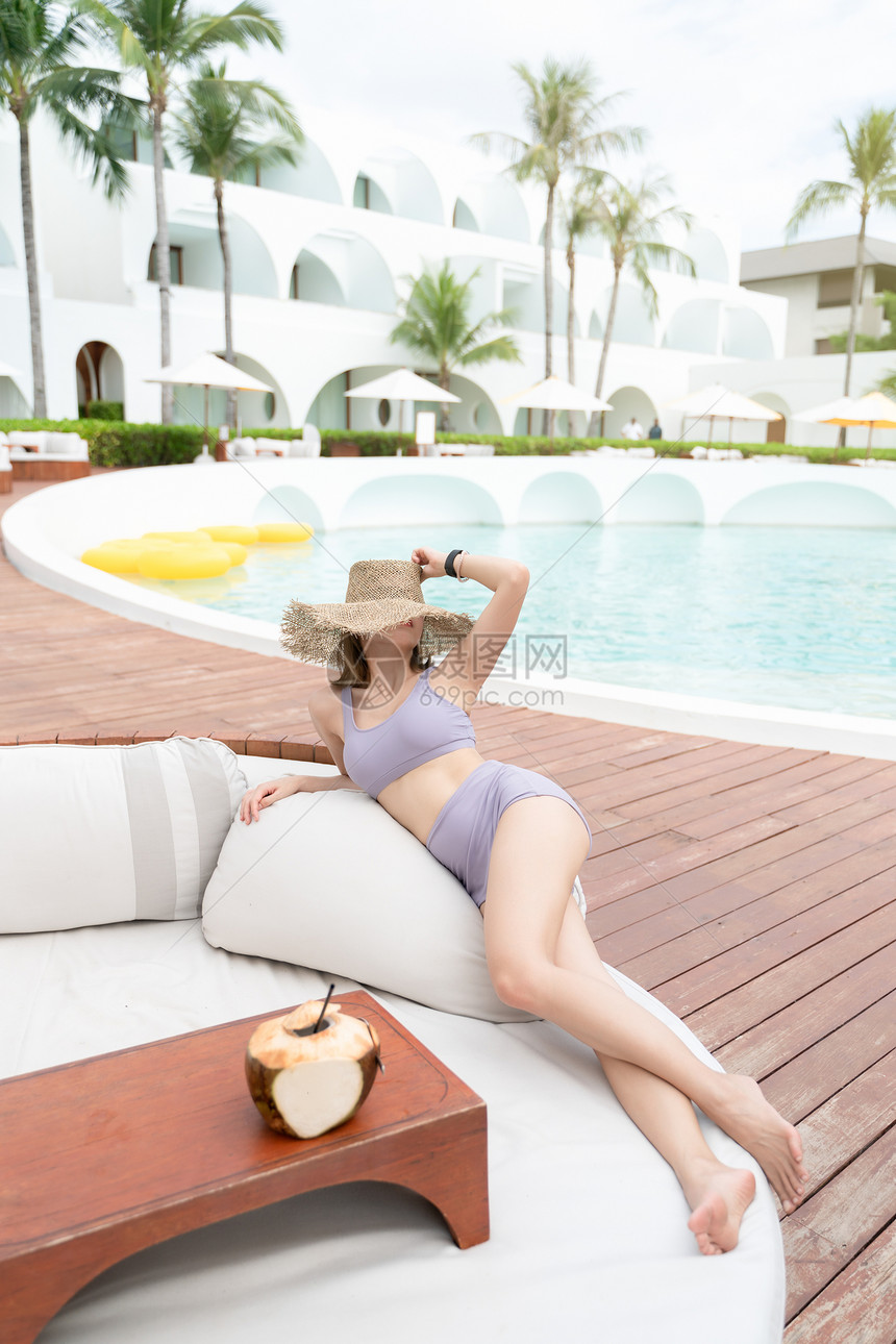 异国情调喝女人在游泳池边放松带椰子暑假酒店图片