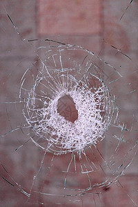 弹孔素材透明折射透明洞在玻璃上形成射线裂缝以血红背景垂直图象和复制空间的垂直图象为挡血红背景的玻璃中弹孔乌克兰背景