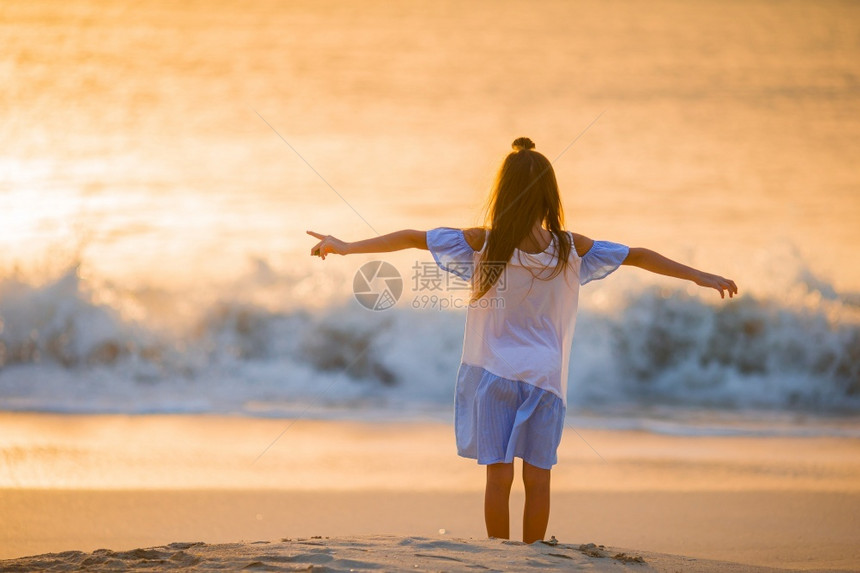 美丽的快乐小女孩在日落的海滩上图片
