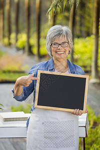 女士室内植物老年在一个温室的美丽成熟女人拿着一个黑板图片