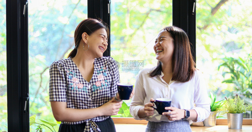 茶微笑随意的两个亚裔妇女喝咖啡和两个开心愉快的女人在咖啡馆闲聊图片