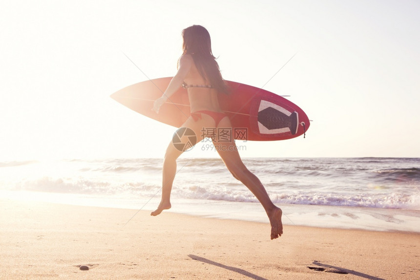 木板夏天白种人热辣的冲浪女孩在海滩上奔跑与她的冲浪板在日落海女孩图片