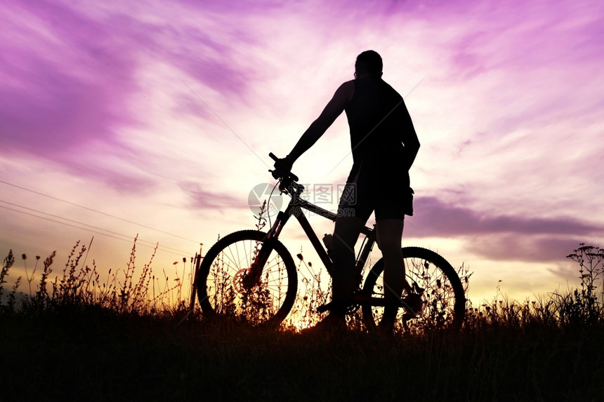 日落时骑自行车在野外停留的旅客喘息轮廓图片