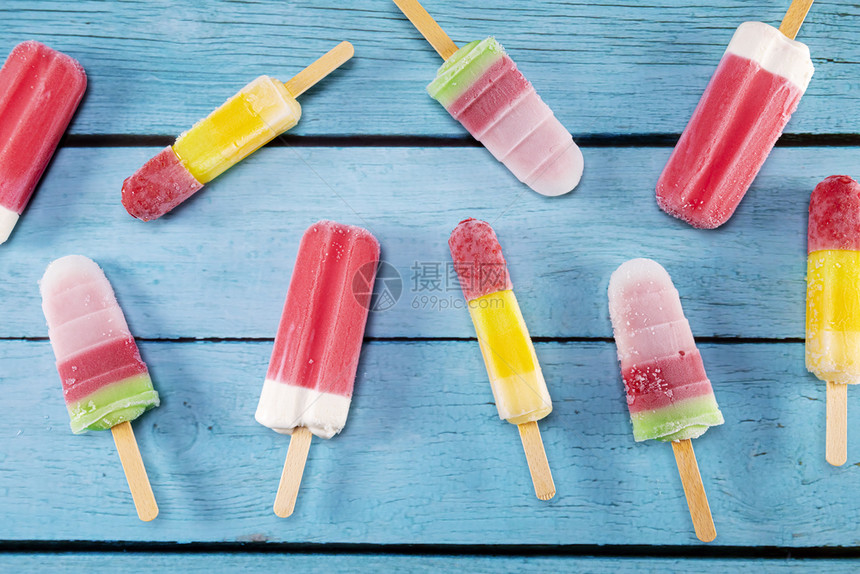 鲜花多彩的水果冰淇淋棒看起来新鲜可吃放在蓝色旧年木地板上夏天甜点复古的图片