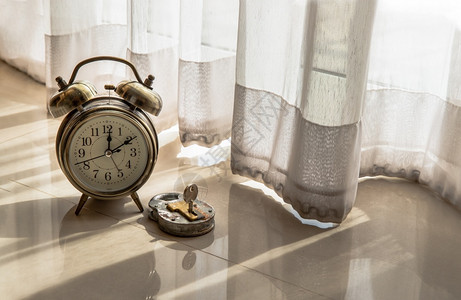 价值对等放松古老的闹钟和旧式铁板锁被放在房间地板上底通过美丽的背景幕帘早日亮光对灯希望和时间价值的概念有感知复制空间选择焦点手表钥匙背景