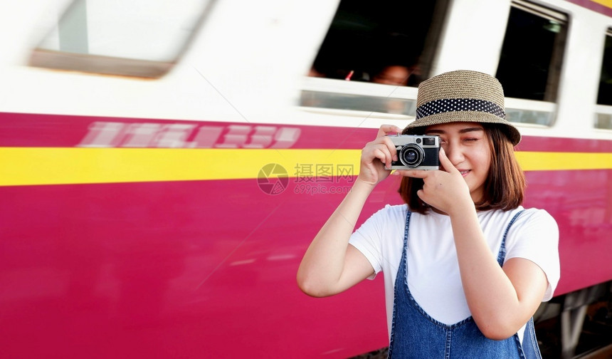 年轻亚洲女旅游客在平台上用旧相机照拍火车背景模糊站里充满着旅行的生活方式概念和潮流观感这些照片与月光摄影机一起拍亚洲人幸福服用图片