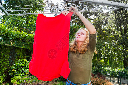 荷兰语家打扫白种女孩在户外洗衣线上挂服图片