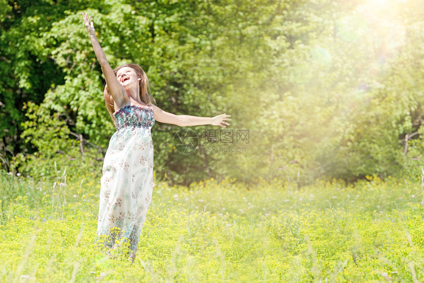 积极的福利快乐年轻女子在绿草地上举起双臂跳跃乐趣图片