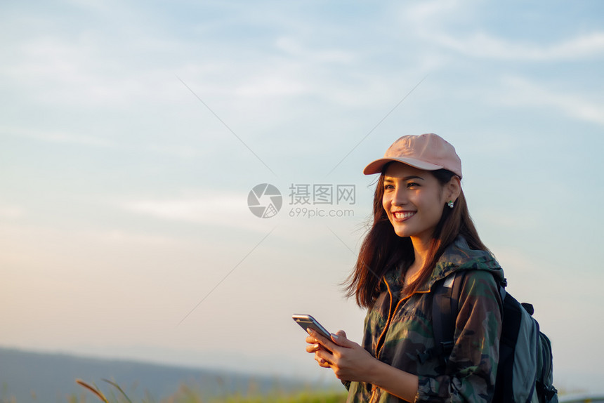 景观年轻的背着明亮包亚洲女在背景山上的旅游行者背后看使用智能手机的女从后面看图景假期图片