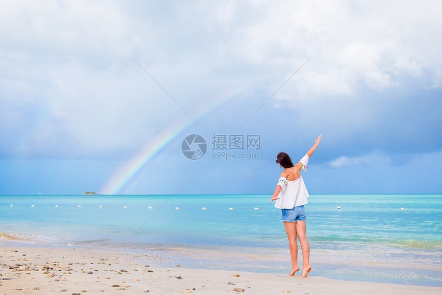 水快乐的美丽女人在海滩上美丽的彩虹在海面上美丽的幸福女人在海滩上美丽的彩虹在海面上图片
