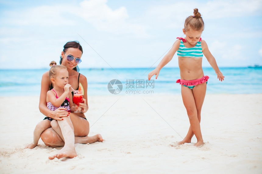 小女孩和年轻母亲在热带白沙滩玩耍图片