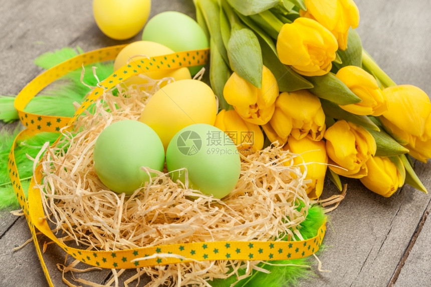 目的以东鸡蛋和黄郁金香在木制桌子上的照片象征图片