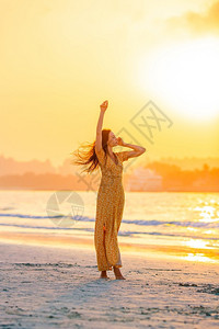 沙滩上日落时的女人图片
