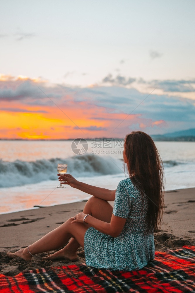 休息乐趣日落时在海滩上的年轻女子躺在海滩上享受暑假看着海的夏天假期图片