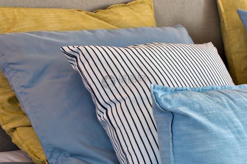 在卧室床上黄色和浅蓝枕头的特写图片