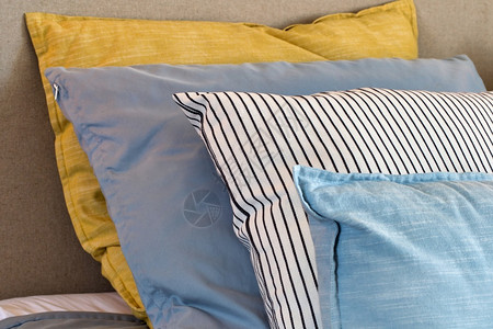 在卧室床上四个黄色和浅蓝枕头的特写图片