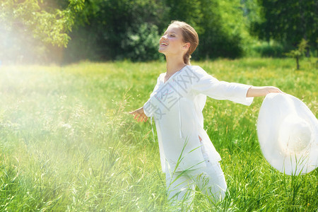 幸福夏天自然穿着白衣的快乐女青年在绿草地上戴着白帽子奔跑图片