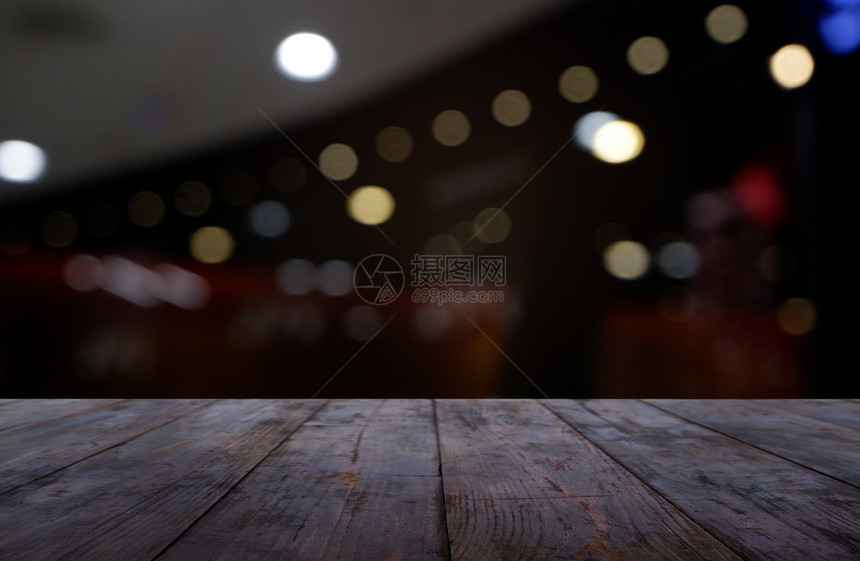 您的电灯泡散焦在咖啡馆和店内部的抽象模糊背景面前的空暗黑木桌可用于展示或调制产品图像Views图片